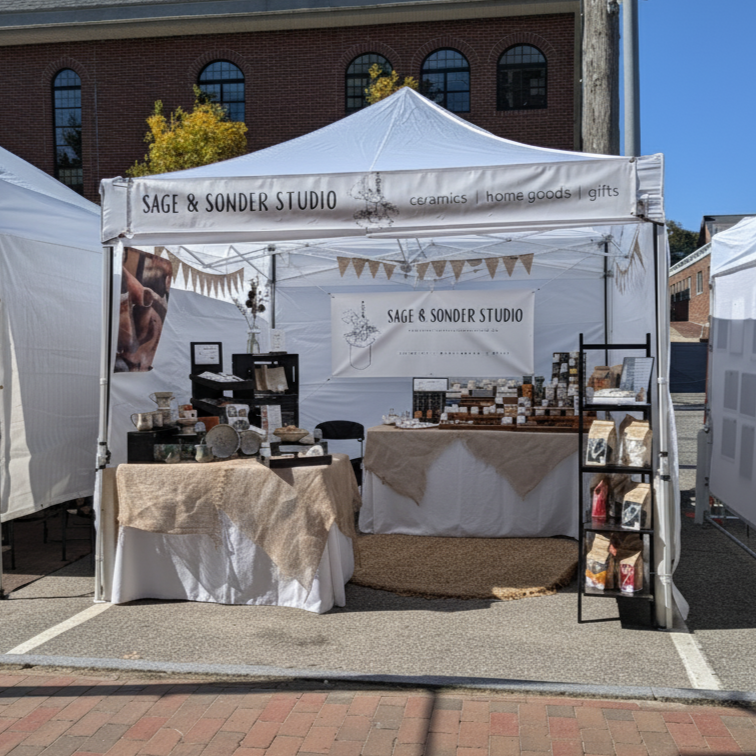 Sage & Sonder Studio's outdoor market booth set up displaying various items.