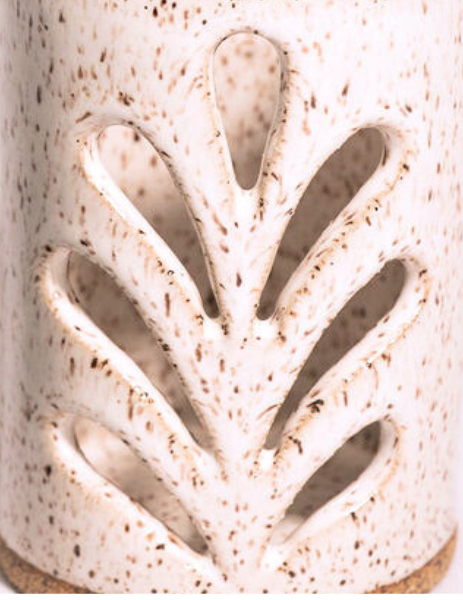 Close-up of a ceramic lantern with leaf-like pattern cut out.