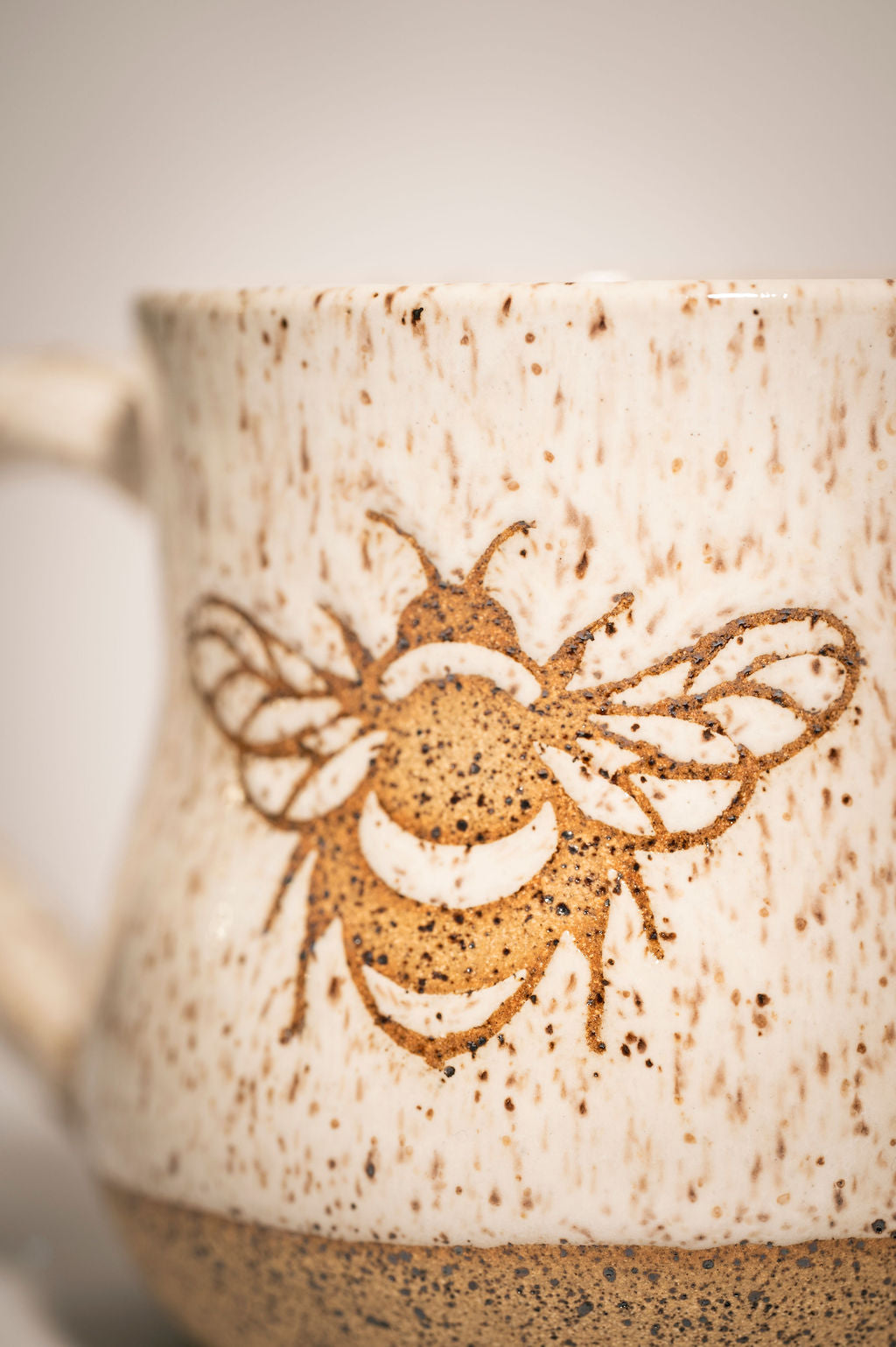 Ceramic mug with a bee design on a speckled beige background