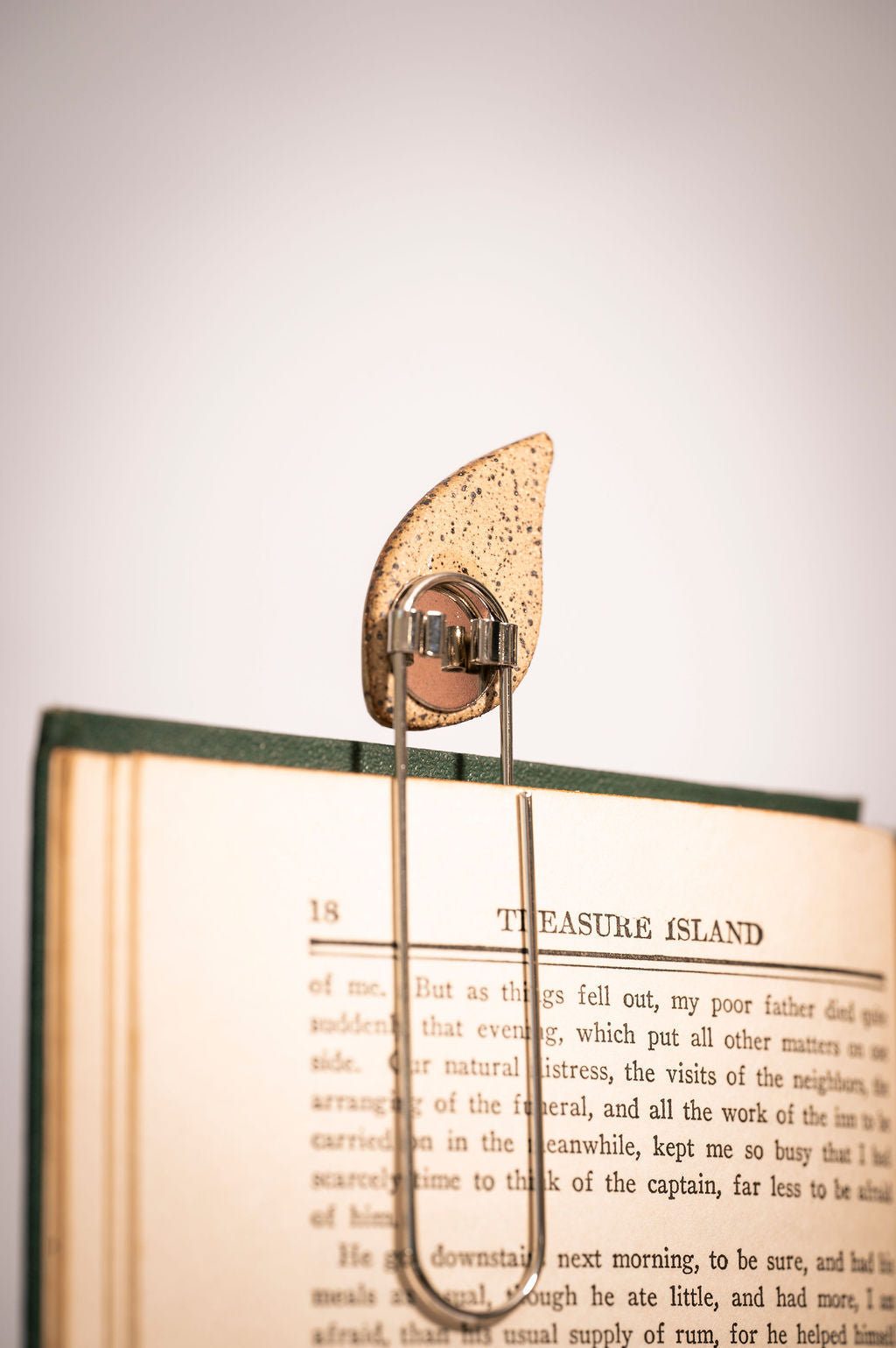 Back of a ceramic leaf-shaped bookend on an open book with visible text.