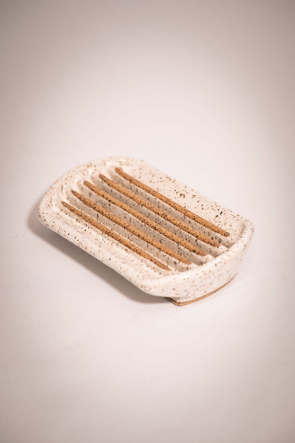 Rectangular white speckled ceramic soap dish with rounded edges.