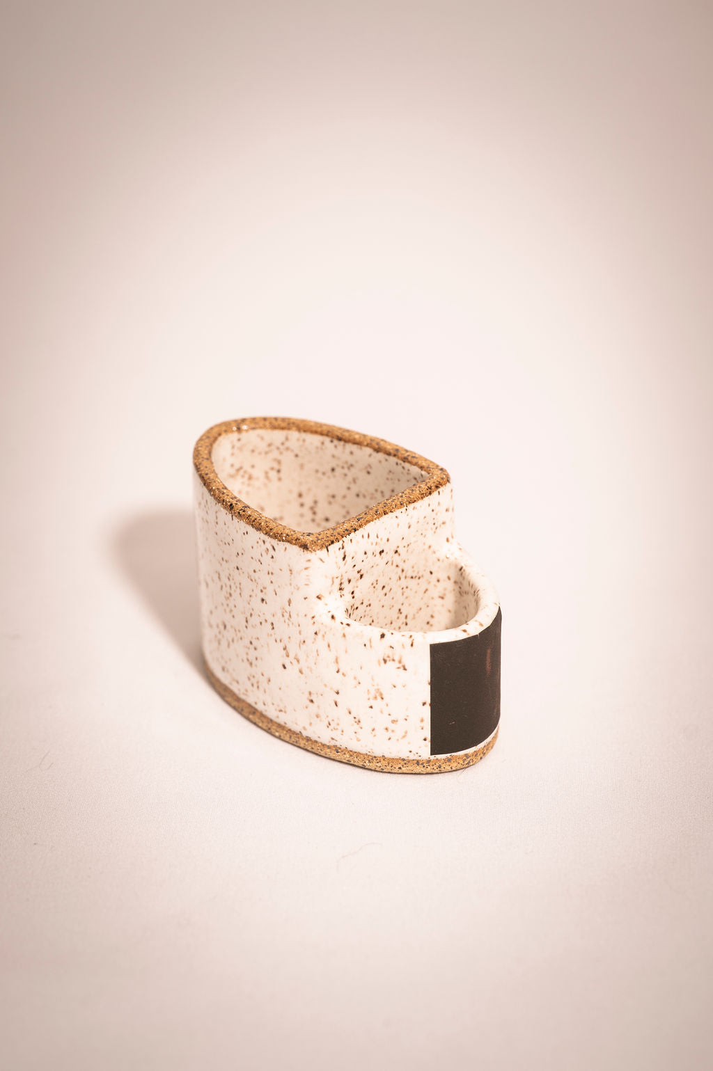 Empty speckled white ceramic match holder.