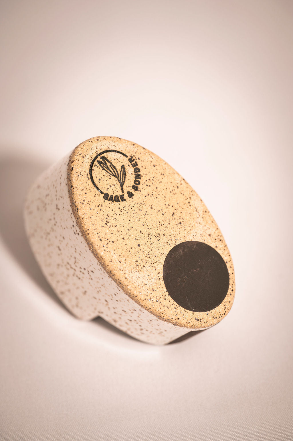 Bottom of speckled white ceramic match holder showing logo and striking sticker for lighting matches.