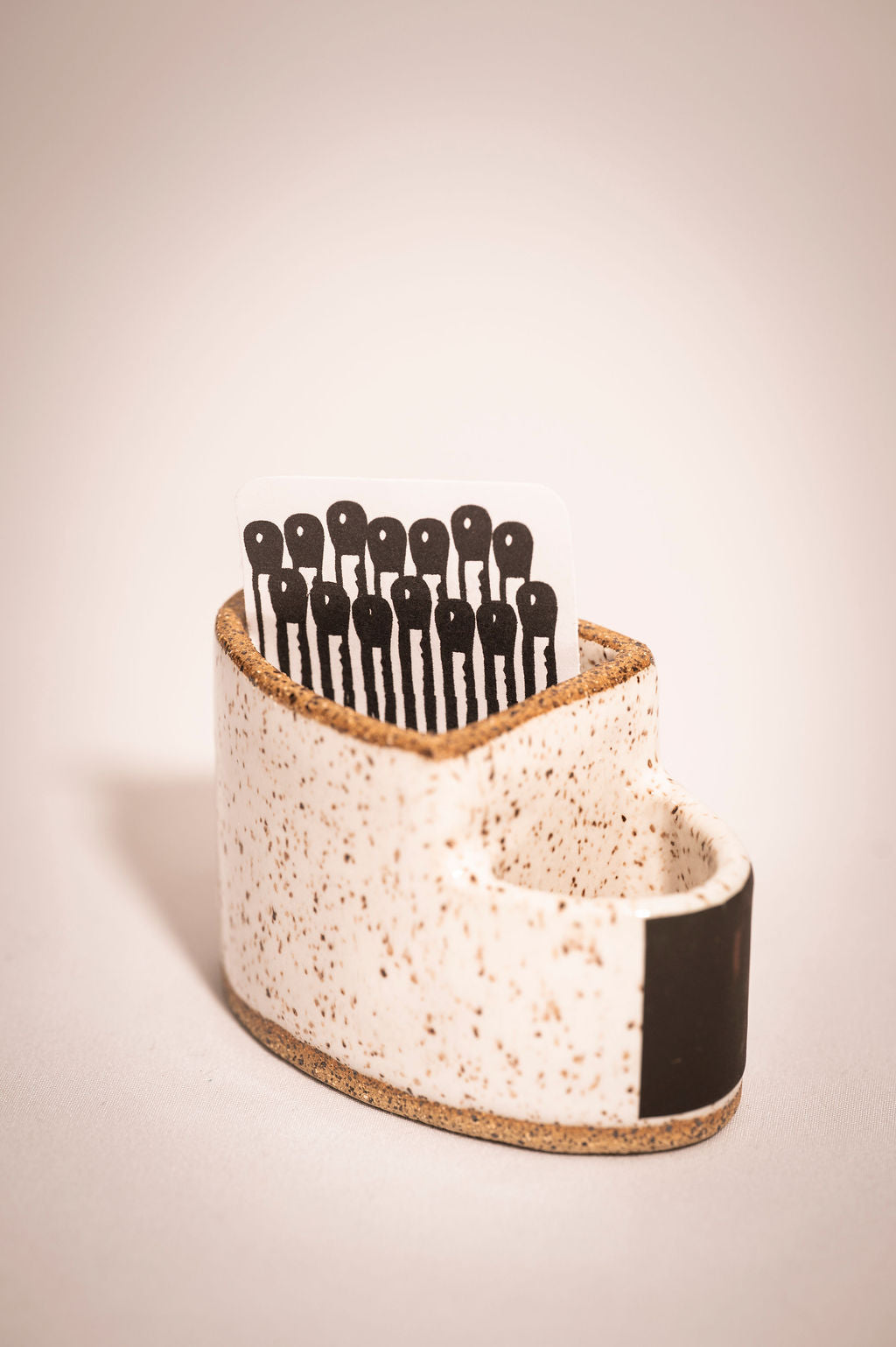 Ceramic match holder showing a paper insert where the matches go.