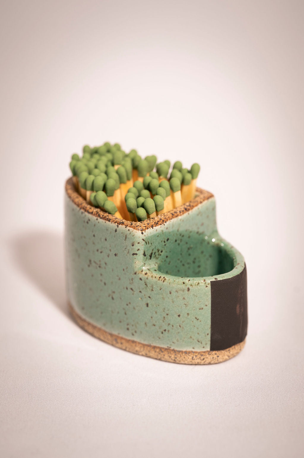 Speckled turquoise ceramic match holder witch matches.