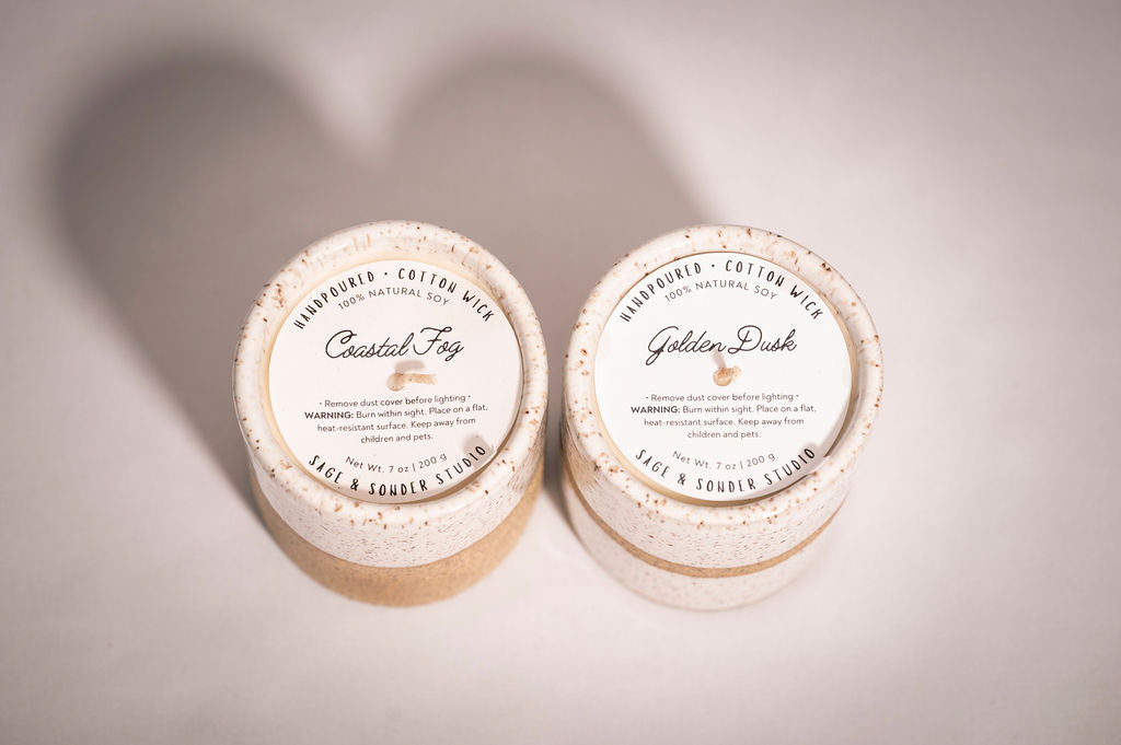 Hand poured candles in a ceramic vessel, looking at the top of the vessel where the scent names are listed on dust jackets. 