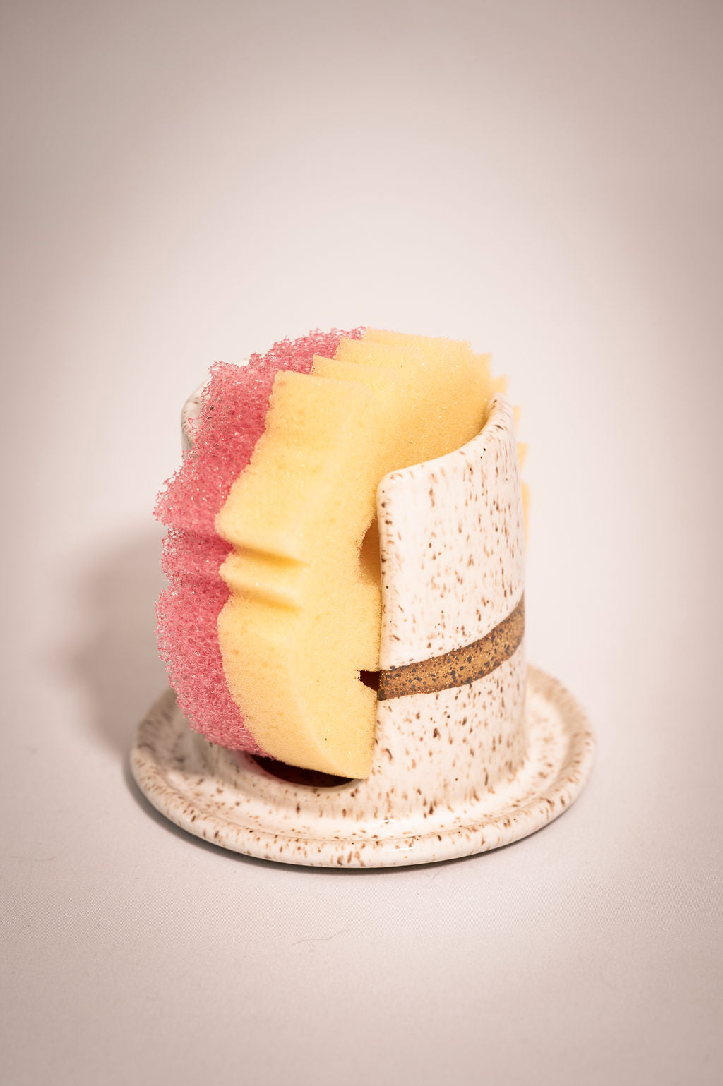 White speckled ceramic sponge holder showing that it fits a "sponge mommy" size sponge.