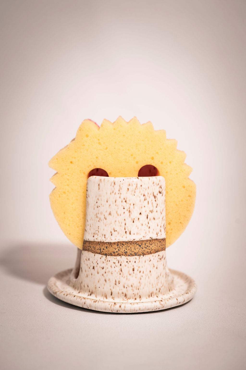 White speckled ceramic sponge holder showing how a "sponge mommy" brand sponge fits.