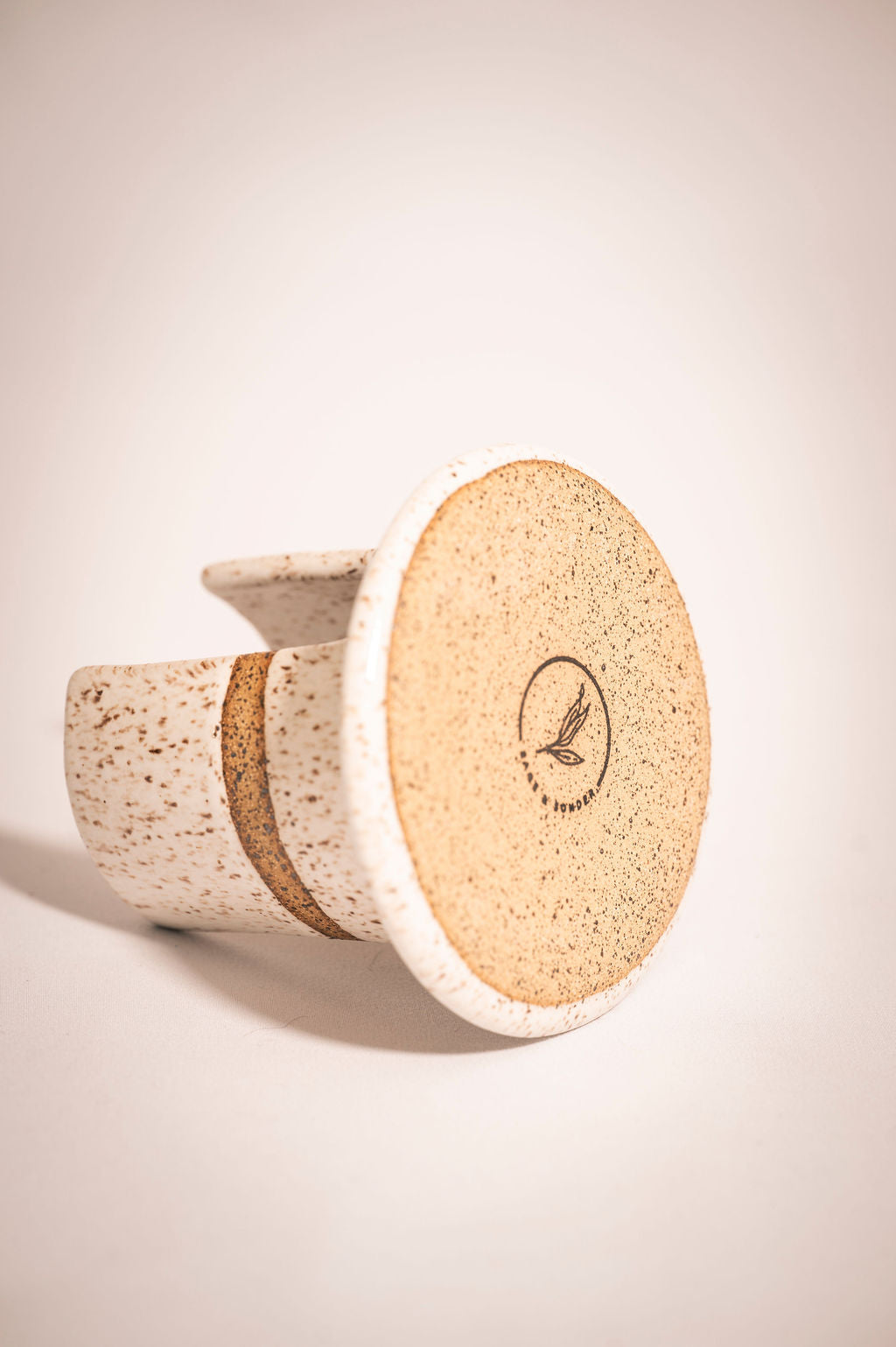 White speckled ceramic sponge holder bottom showing stamped logo.