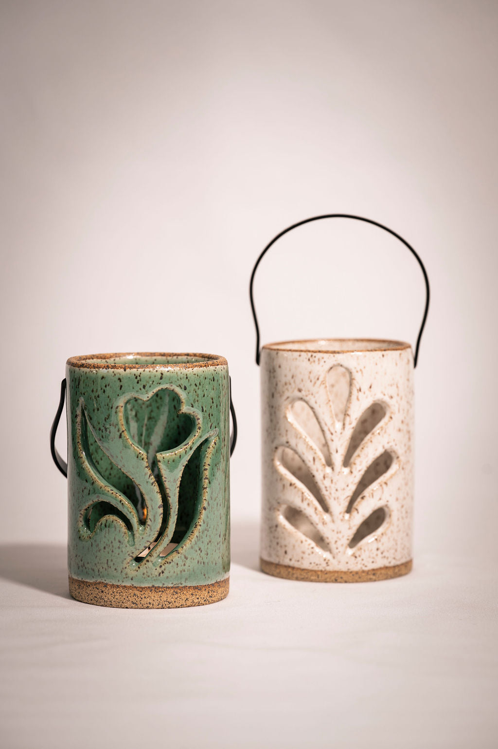 Two ceramic lanterns with leaf designs on a plain background