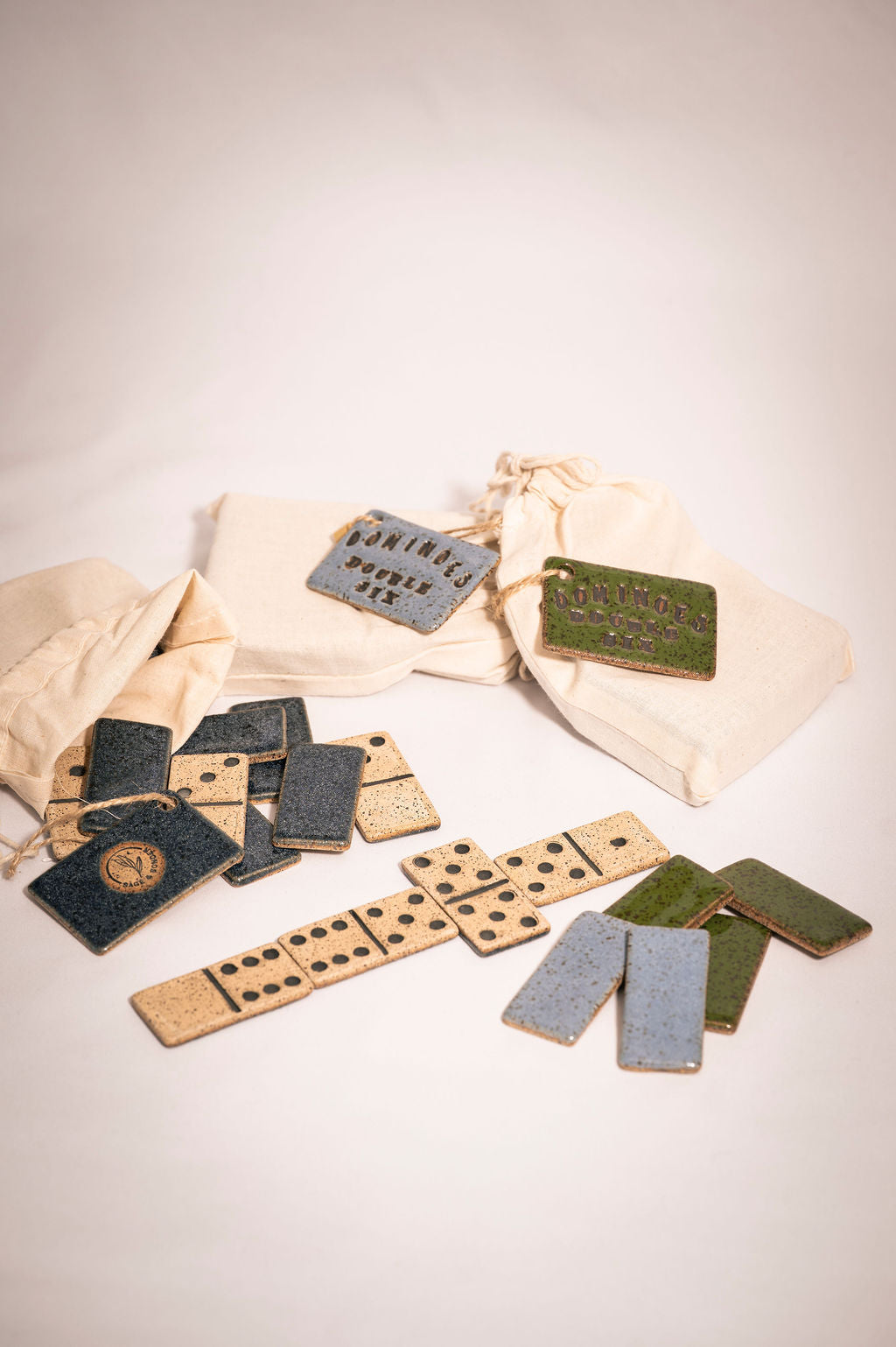 Collection of ceramic dominoes pieces spread on a table showing varioustiles in play on a light background