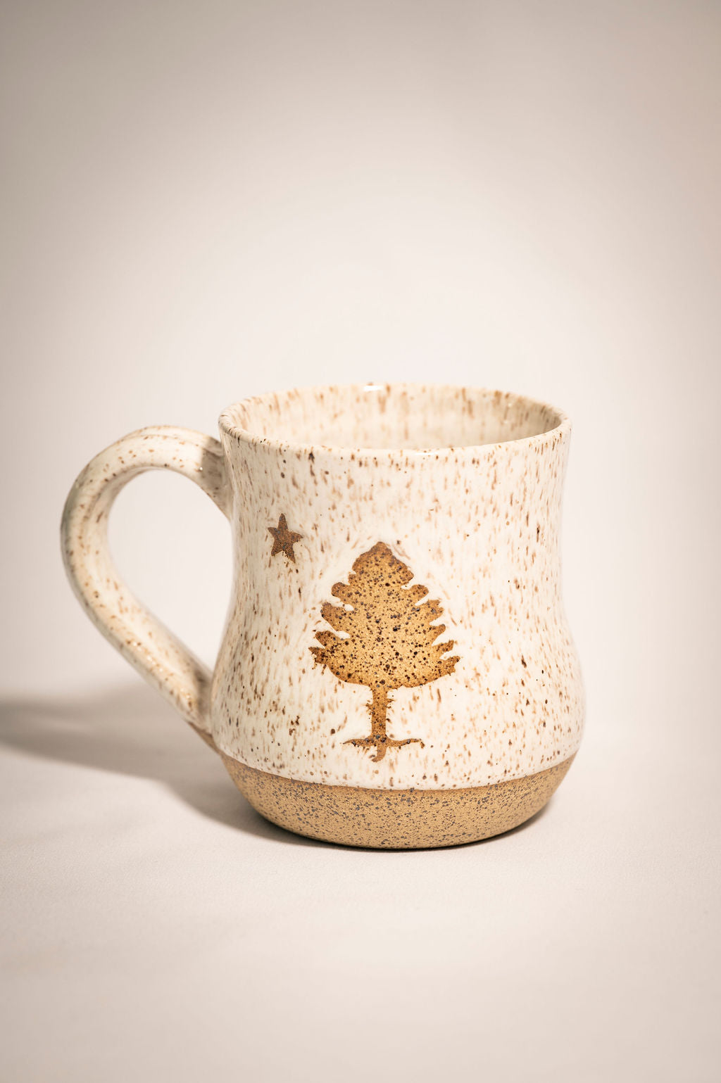 Ceramic white speckled mug with a maine state tree design 
