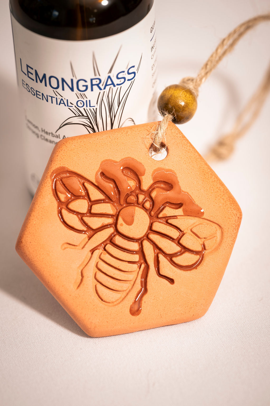 A clay medallion with a bee stamped on it with essential oils soaking into the piece to show how the clay diffuser works.