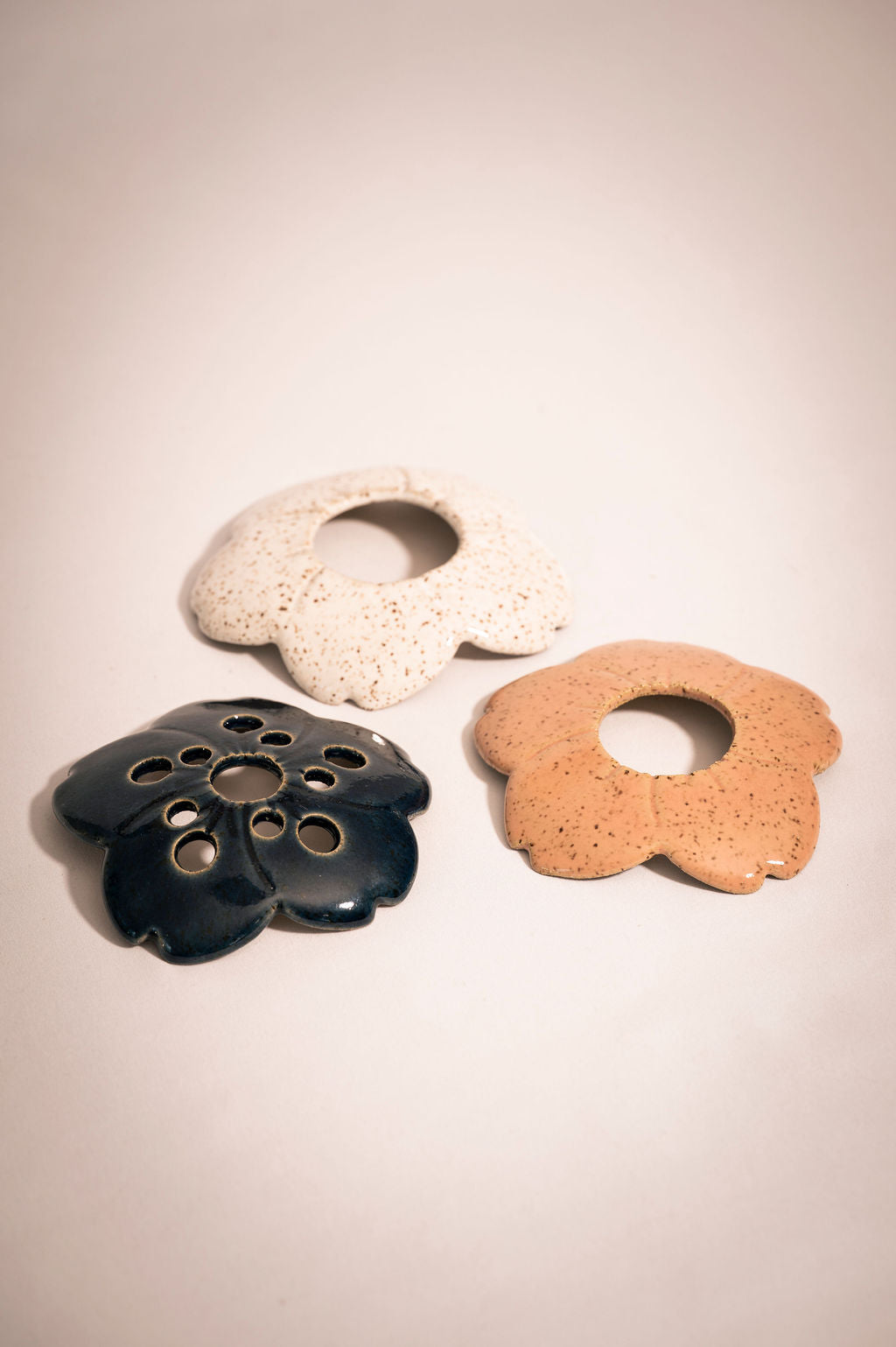 Three ceramic flower frogs in blue, white, and pink