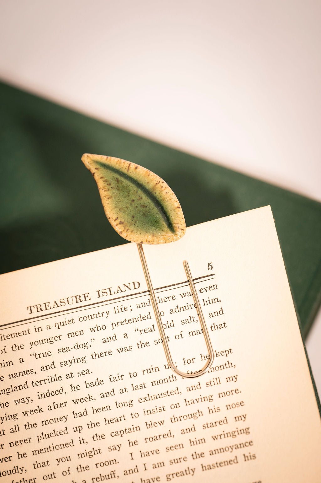 Leaf-shaped bookmark on a book with a green fabric background