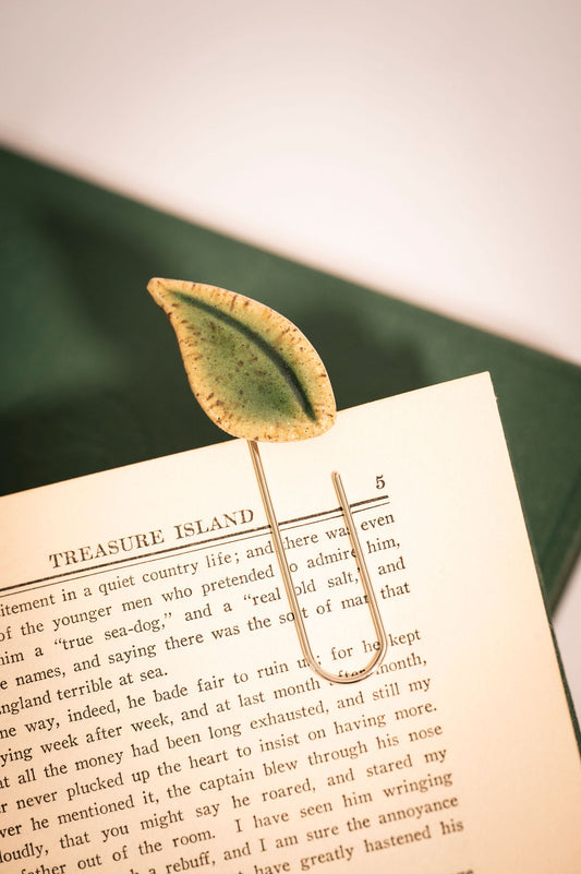 Leaf-shaped bookmark on a book with a green fabric background
